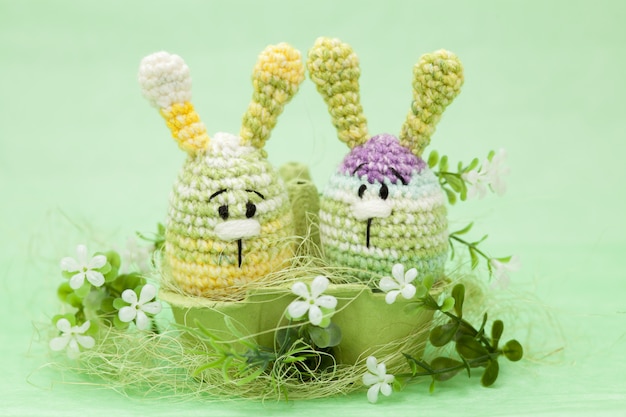 Knitted Easter decor eggs, flowers , bunny on a green background, amigurumi