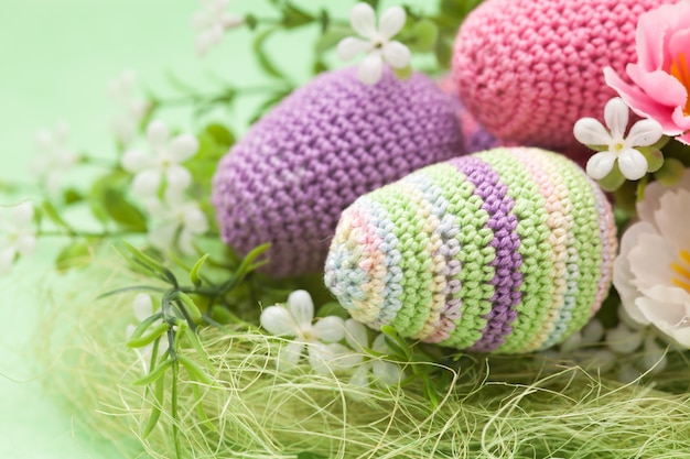 Knitted Easter decor eggs, flowers on a green background, handmade