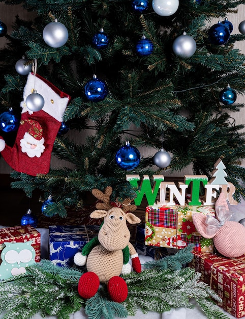 Knitted elk cute moose toy against the background of a New Year's garland knitted hare and elk on a Christmas tree