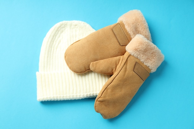 Knitted hat and mittens on blue background.