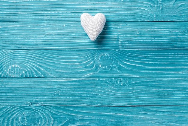 Вязаное сердце на синем деревянном фоне