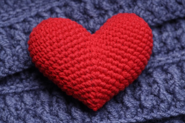 Knitted heart lies on a blue knitted napkin. Love concept. High quality photo