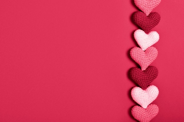 Knitted hearts in a row lie on a red background Background for Valentine's Day