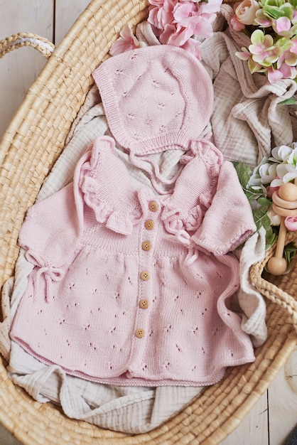 編み物用の子供服とアクセサリーのニット。針仕事と編み物。趣味と創造性。子供用ニット。手作りのピンクのドレスとキャップ。