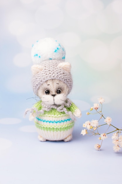 A knitted kitten with knitting needles colored balls of thread in a basket Creative workshop on needlework handmade