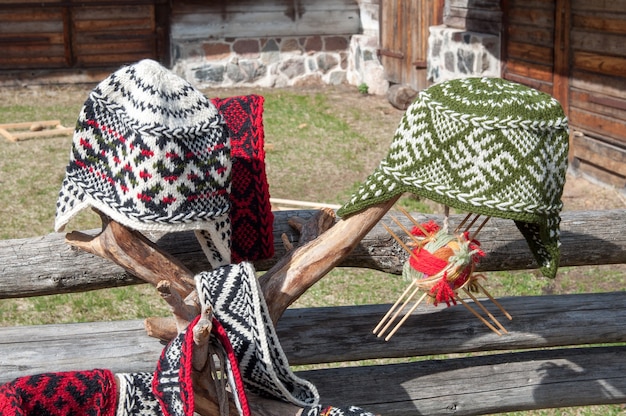 Фото Вязаная латышская шапка с орнаментом на деревянном заборе снаружи