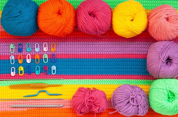 色とりどりの糸ピンとさまざまな編み針のボールを使って編んだ多色の手作り生地