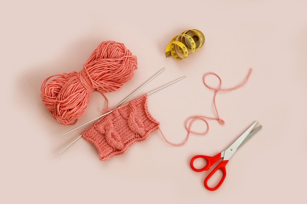 knitted pattern on knitting needles with scissors and measuring tape