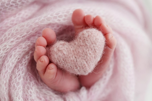 아기의 다리에 니트 핑크 하트 핑크색 양모 담요로 태어난 신생아의 부드러운 발 발가락 확대 사진 신생아의 발 매크로 사진 신생아의 작은 발