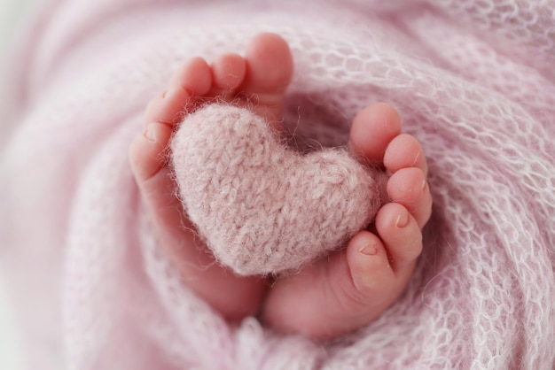 아기의 다리에 니트 핑크 하트 핑크색 양모 담요로 태어난 신생아의 부드러운 발 발가락 확대 사진 신생아의 발 매크로 사진 신생아의 작은 발