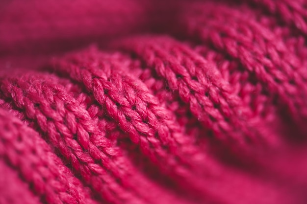 Knitted pink sweater with braid pattern close up. Winter season. Selective focus.