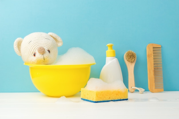 Orso polare lavorato a maglia che fa il bagno in una bacinella gialla.