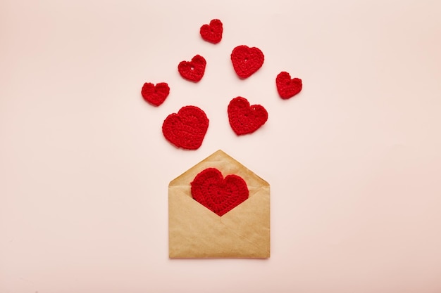 Knitted red hearts fly out of the envelope background for valentines day