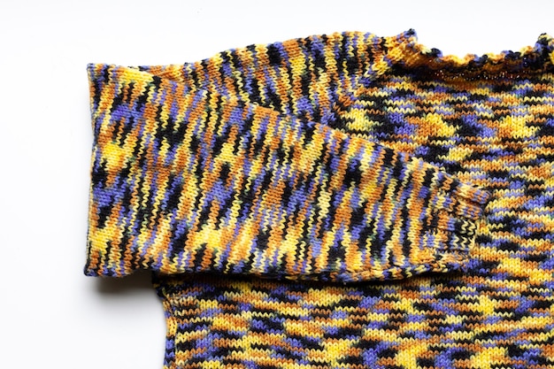 Knitted sleeve on a knitted sweater, blue yellow black brown color.