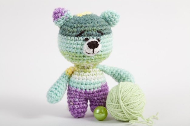 Вязаный маленький медведь на белом фоне. Ручная вязаная игрушка. Amigurumi