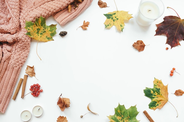 Maglione lavorato a maglia foglie autunnali bastoncini di cannella candele su sfondo bianco composizione autunnale piatta