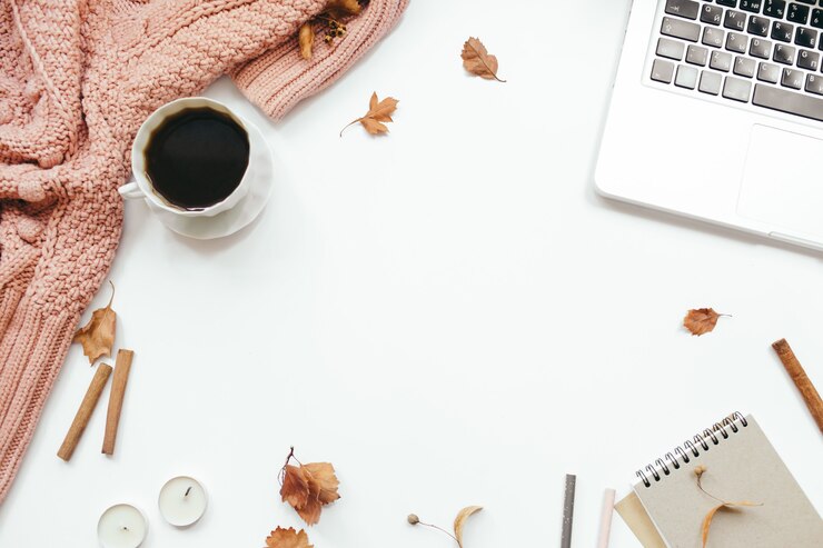 Photo knitted sweater, cup of coffee, laptop, notebook, autumn leaves, cinnamon sticks, candles on white background. autumn composition. home office desk workspace. flat lay, top view, copy space