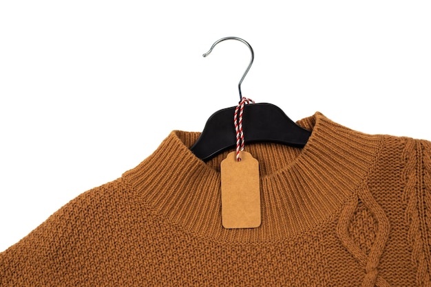 Il maglione lavorato a maglia si blocca su un gancio nero con un'etichetta isolata on white