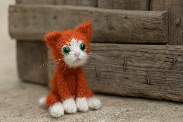 Knitted toy kitten, ginger kitten on the background of the boards