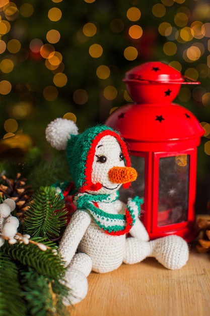 Knitted toy snowman is sitting on the floor near the red lantern