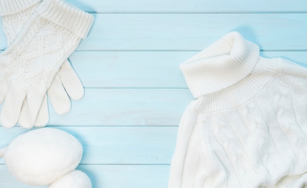Knitted warm white clothes on a light blue wooden background