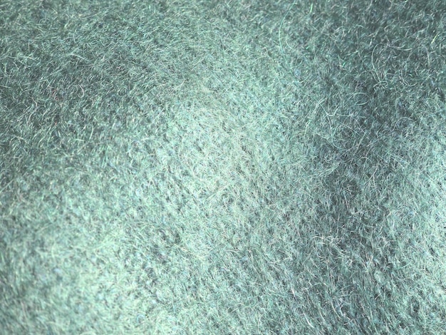 Вязаный шерстяной фон. Теплая зимняя одежда связана из зеленой пряжи марки Angora. Мохнатая куча. Образец вязания.