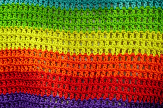 Foto un tessuto di lana a maglia nei colori dell'arcobaleno crochet, cucito a mano, filati multicolori, struttura del maglione, striscia orizzontale