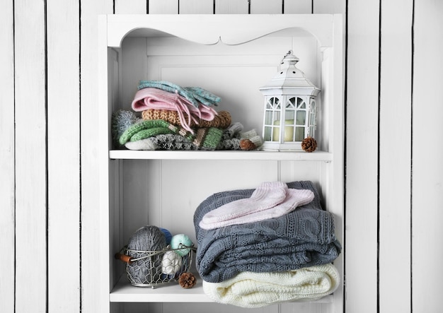 Knitting clothes with accessories on wooden shelf