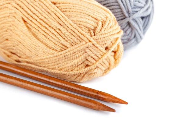 Knitting needles and grey and yellow woolen threads isolated