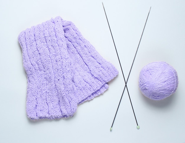 Knitting needles, thread balls, yarn on a gray background