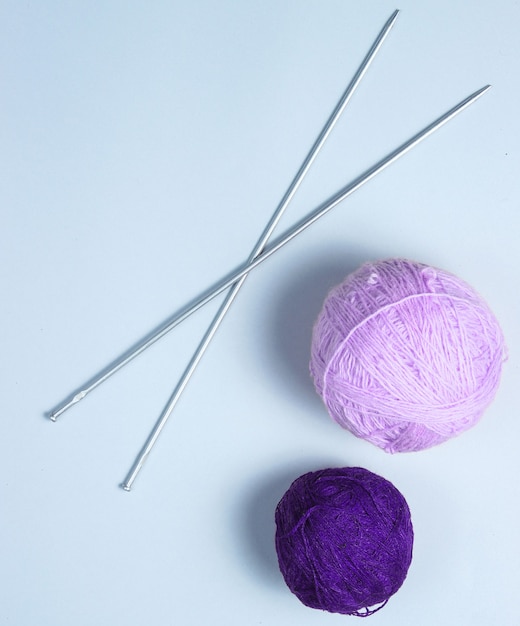 Knitting needles, thread balls, yarn on a gray background