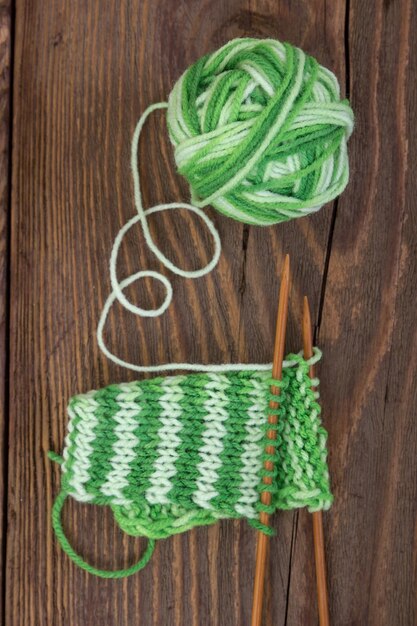 Knitting pattern of green yarn on a wooden background