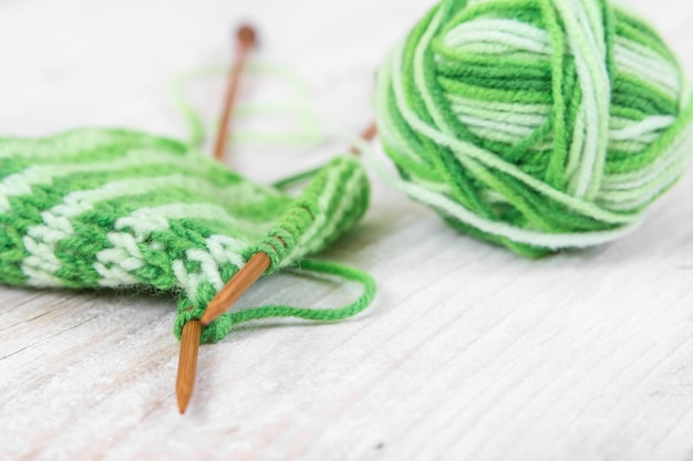 knitting pattern of green yarn on wooden needles and skein