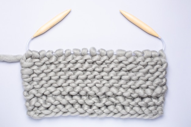 뜨개질 프로젝트가 진행 중입니다. 원사의 공과 뜨개질 바늘로 뜨개질의 조각.