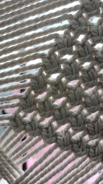 Photo knitting with beige thread made of wool photo in macro mode on the background of a window