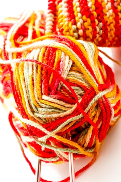 Knitting with multi colored yarn with orange, red, and yellow tones.
