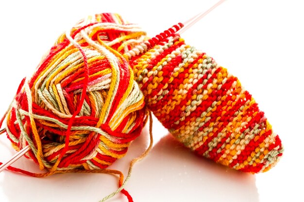 Knitting with multi colored yarn with orange, red, and yellow tones.