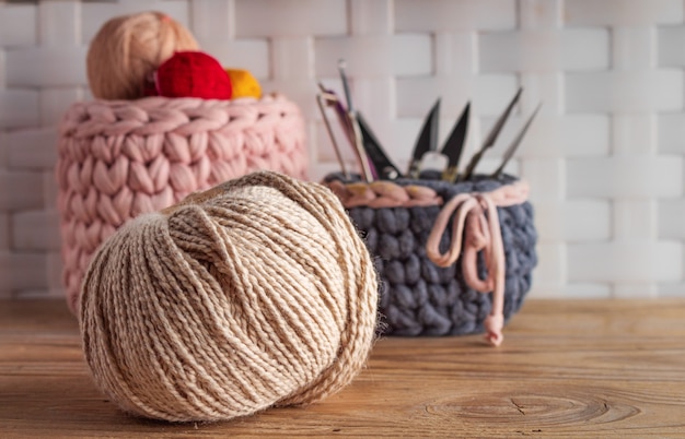 Knitting yarn with knitted baskets on wooden table.