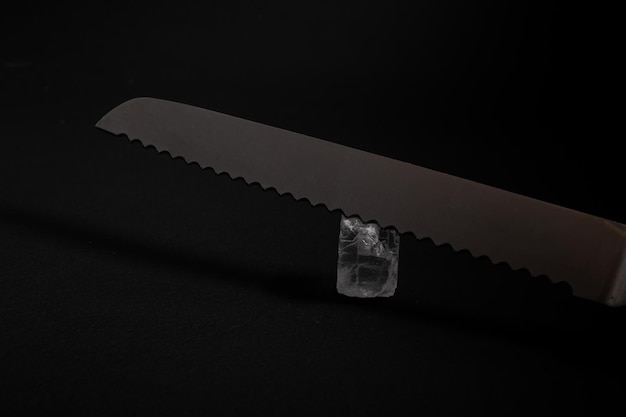 Knives made of metal, silver, lie on a black background with a glare of light