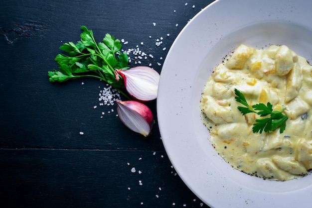 Knoedel van aardappelen onder kaassaus Op een houten ondergrond Bovenaanzicht Vrije ruimte