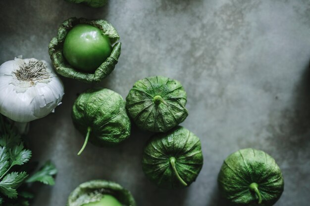 Knoflook en groene tomatillos op een grijze lijst