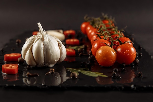 Knoflook knoflook op een zwarte achtergrond met tomaten en champignons