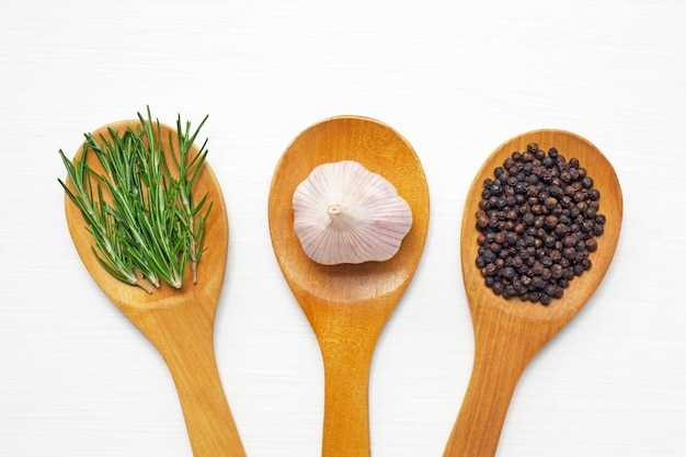 Knoflook met rozemarijn en zwarte die peperbollen op wit wordt geïsoleerd.