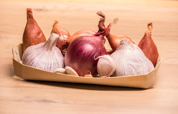 Knoflook uien sjalotten in een kleine houten mand