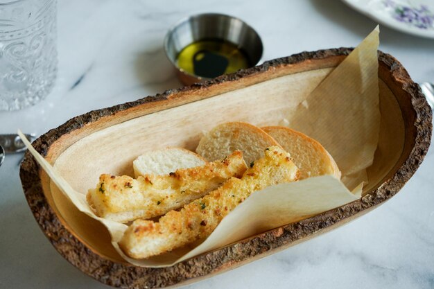 Knoflookbrood in de houten plaat en olijfolie ernaast.