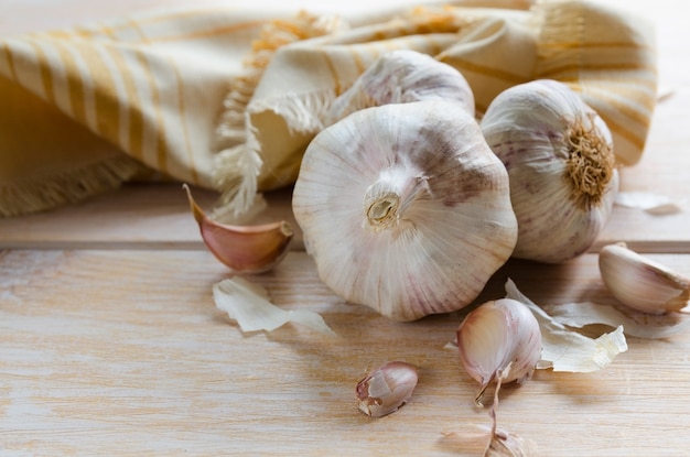 Knoflookteentjes en knoflook lamp met linnen servet op houten achtergrond met kopie ruimte.