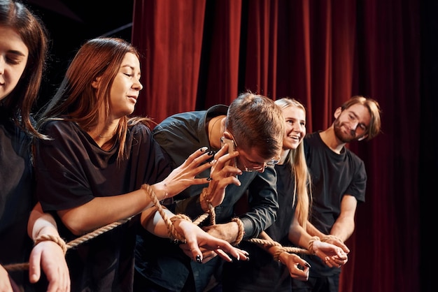 Foto knoop in de handen groep acteurs in donker gekleurde kleding op repetitie in het theater