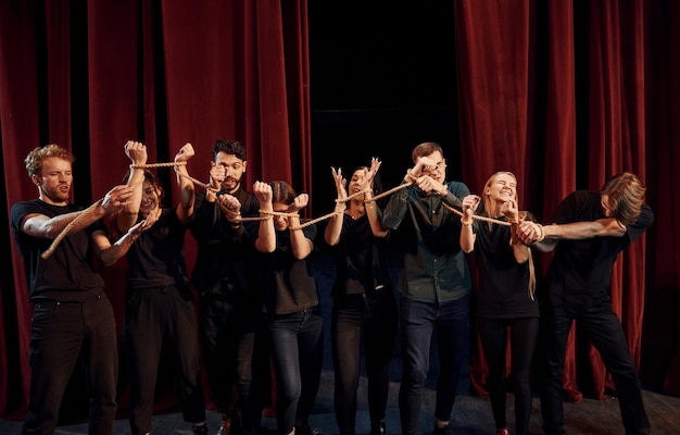 Knoop in de handen Groep acteurs in donker gekleurde kleding op repetitie in het theater