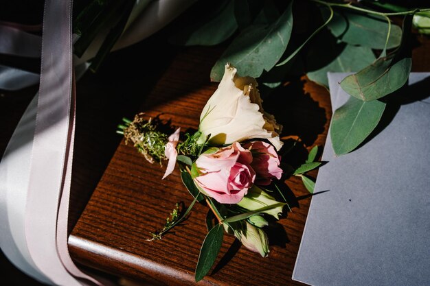 Knoopsgat corsages voor de bruidegom bruiloft accessoire bruid stijlvol boeket bloemen op tafel staande op houten achtergrond Brieven van de bruid en bruidegom plat lag bovenaanzicht