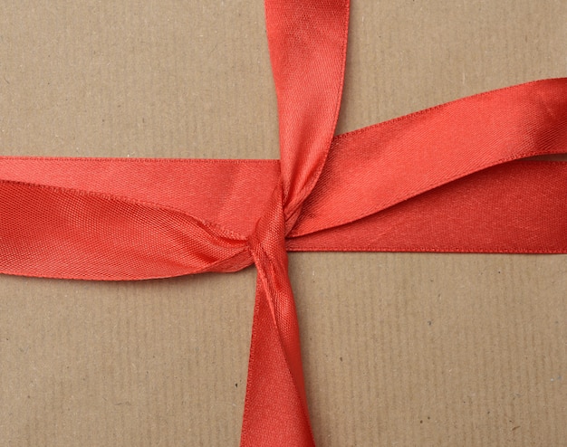 Photo knotted red silk ribbon on brown kraft paper